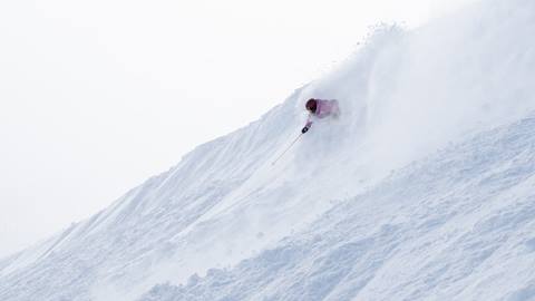 skier riding through steep powder