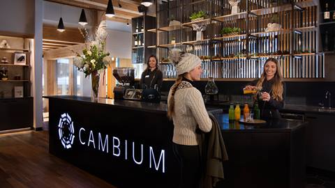 resort staff greet incoming guests at the modern wood front reception desk inside cambium spa