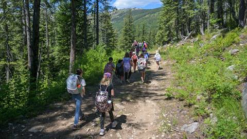 a youth group hikes a forest trail during a summer camp session hosted by the schweitzer children's center