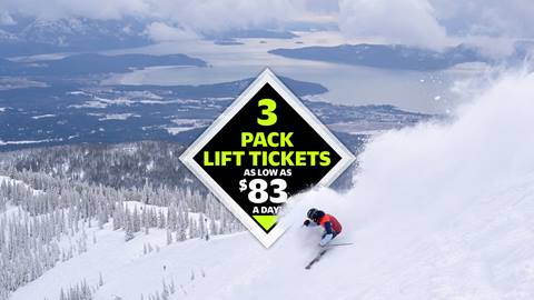 skier riding down steep slope spraying snow with lake pend oreille in the background at Schweitzer with 3-pack deal graphic