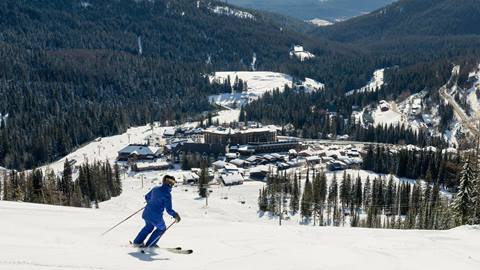 image of skier on groomed run with schweitzer village in the background
