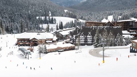 people skiing on slope with hotels in the background