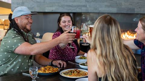 group of people cheersing their glasses over delicious food at Crow's Bench