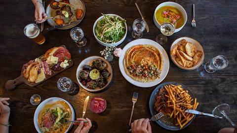 dark colored table filled with plates full of food and glasses with drinks