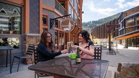 two people outside of gourmandie with glasses of champagne