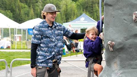 Schweitzer employee helping a young guest on the climbing wall