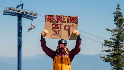 woman in snowboard gear holding sign for pass sale deadline