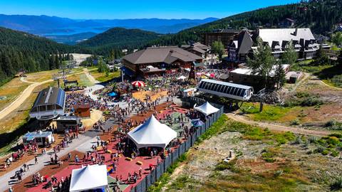 An aerial view shows a large crowd gathered among white tents and resort buildings during Fall Fest at Schweitzer