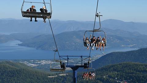 People on chairlift at Schweitzer with beer raising their glasses to other people