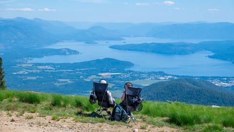 couple sitting in camping chairs with headphones while looking out over Lake Pend Oreille