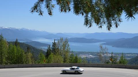 vintage car driving down mountain road to  get to Schweitzer with view of lake pend oreille