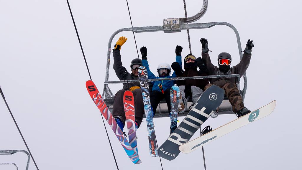 image of people on chairlift with their arms raised and happy