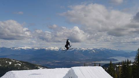 skiers doing trick off jump in the terrain park at Schweitzer