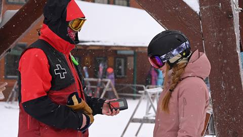 patroller talking to ski guest about beacons