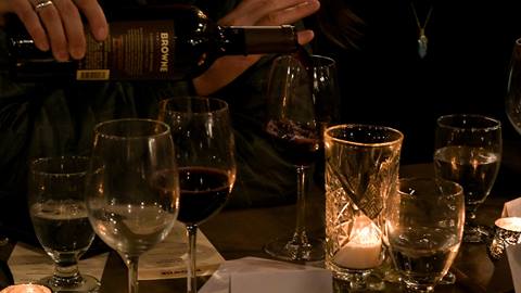 wine being poured into a wine glass at dinner with candlelight