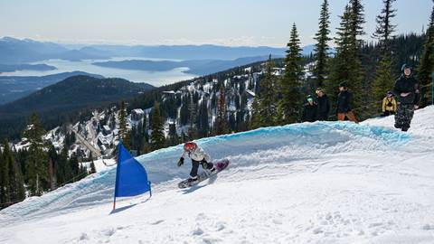 snowboarder racing through banked slalom course at Schweitzer