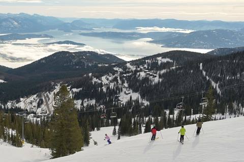 group of skiers at the top of a ski run with lake pend oreille in the background