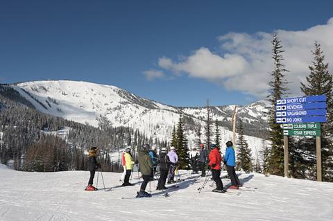 group of skiers at sign with slopes in the background