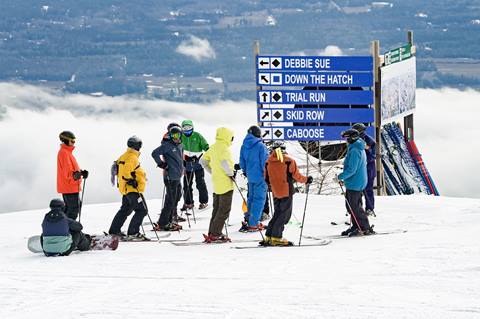 group of skiers together by a sign of trail names