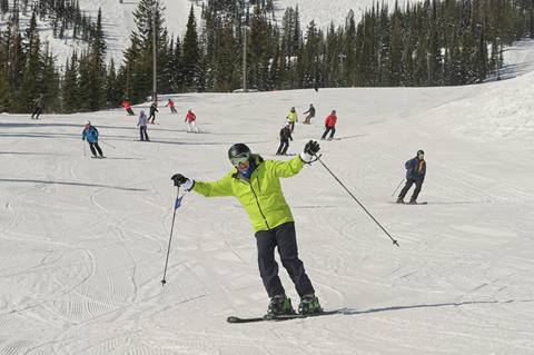 skier coming down slope raising arms 