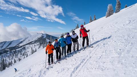 group of skiers on run smiling with view of slopes in the background