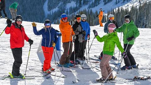 group of skiers stopped and waving at camera