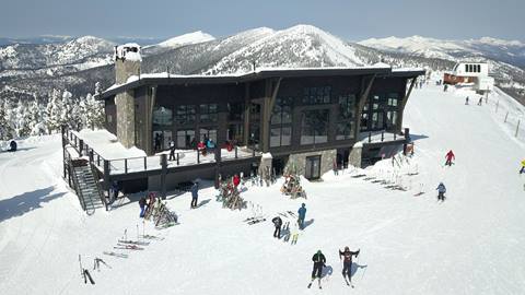 An aerial view shows skiers and snowboarders gathered on the snow outside the Sky House lodge at Schweitzer.