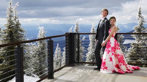A bride and groom pose together on a snowy outdoor balcony at Schweitzer.