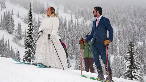 A bride and groom smile at each other while skiing down a snowy slope at Schweitzer.