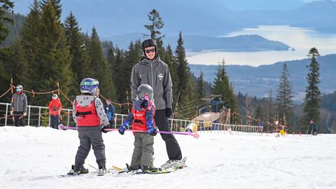 Ski instructor guiding two young children in winter program on the snow on Schweitzer's bunny hill