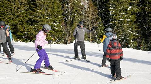 an instructor teaches a small group of kids during kids group snowboarding & ski lessons at schweitzer mountain resort