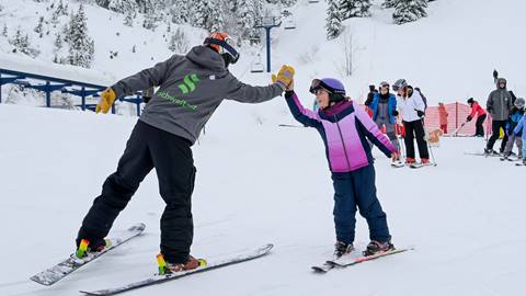 an instructor gives a high-five to a young student during kids group snowboard & ski lessons at schweitzer mountain resort