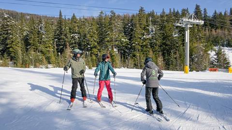 three students stand with an instructor during adult group ski lessons at schweitzer mountain resort