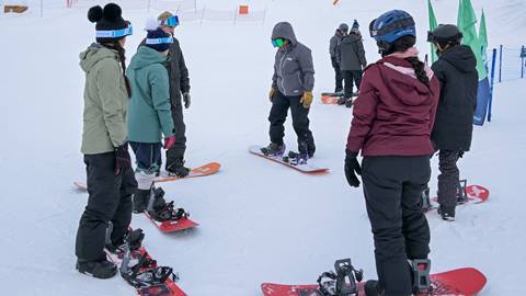 a group of students stands with their instructor during adult group snowboard & ski lessons at schweitzer mountain resort
