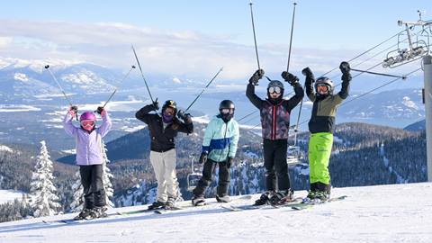 a group smiling at the top of schweitzer mountain during mountain xplorers ski program on a sunny winter day