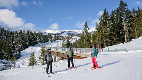 two adults in ski lesson with schweitzer mountain in the background
