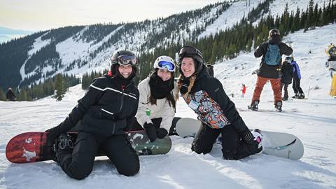 three women pose with their snowboards during an adult group snowboard lessons at schweitzer mountain resort