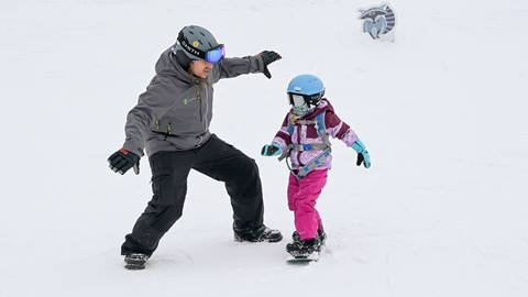 an instructor guides a young child during a private snowboarding & ski lesson at schweitzer mountain resort