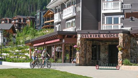 2 mountain bikers in front of the Selkirk Lodge at Schweitzer in summer