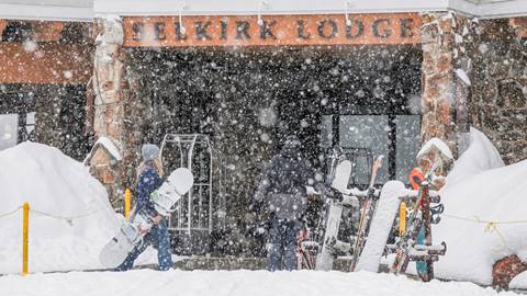 guests carrying snowboards enter selkirk lodge at schweitzer during a snowy winter day