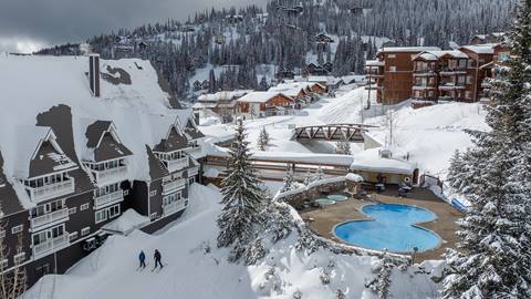 winter view of selkirk lodge at schweitzer with the outdoor pool and nearby village buildings covered in fresh snow
