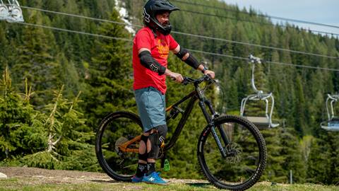 Rider fully equipped with helmet, elbow pads, and knee pads, showcasing Schweitzer's full mountain bike gear rental package