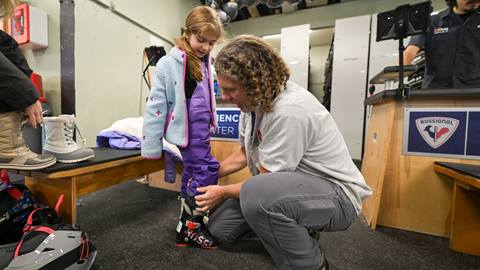 an employee helping a young girl put on ski rentals boots at the schweitzer mountain rental center