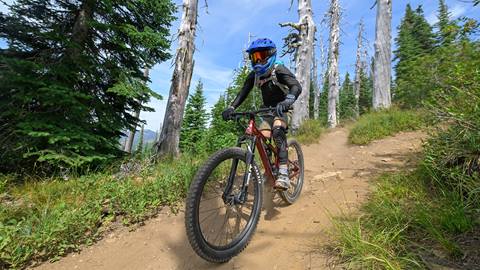 a rider in full gear handles technical dirt trails with premium mountain bike rentals at schweitzer