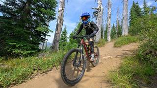 a rider in full gear handles technical dirt trails with premium mountain bike rentals at schweitzer