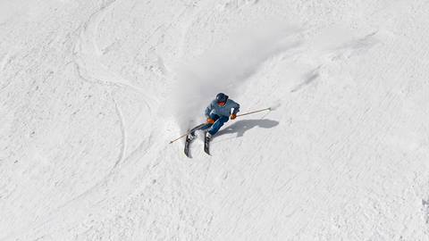Skier carving into fresh powder on Schweitzer's snowy slopes with high-performance ski rental gear