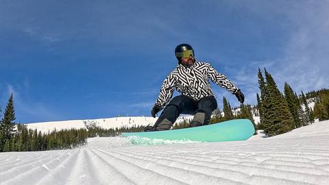 Snowboarder gliding across groomed corduroy terrain in Schweitzer's winter snowboard rental zone