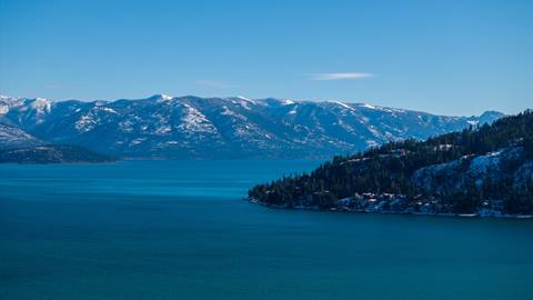 drone image of lake pend oreille with view of snow covered cabinet mountains