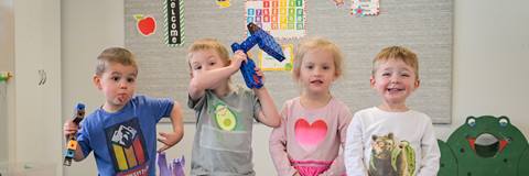 Preschool children smiling and posing for a group photo inside Schweitzer's children center