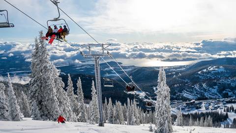 person skiing down run under chairlift with lake background